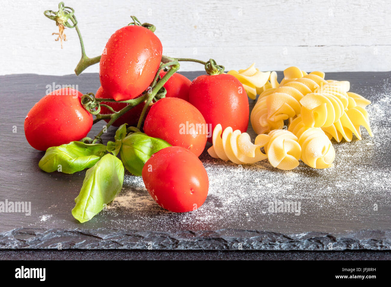 Fusilli fresh tomatoes and basil the ingredients for a typical dish of Italian pasta Stock Photo