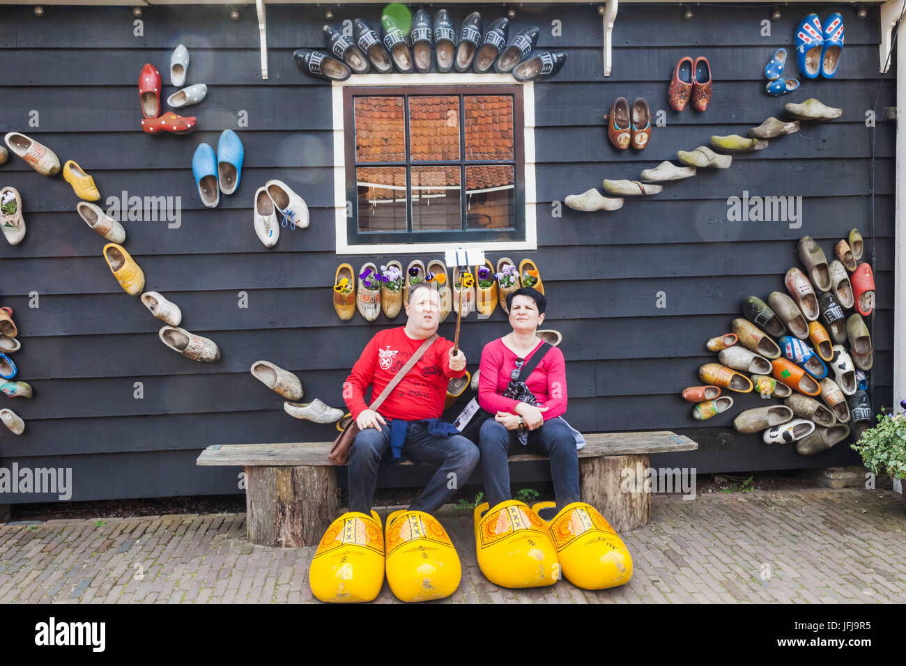 Europe, Netherlands, Zaandam, Zaanse Schans, Tourist Couple Posing with Giant Clogs Stock Photo