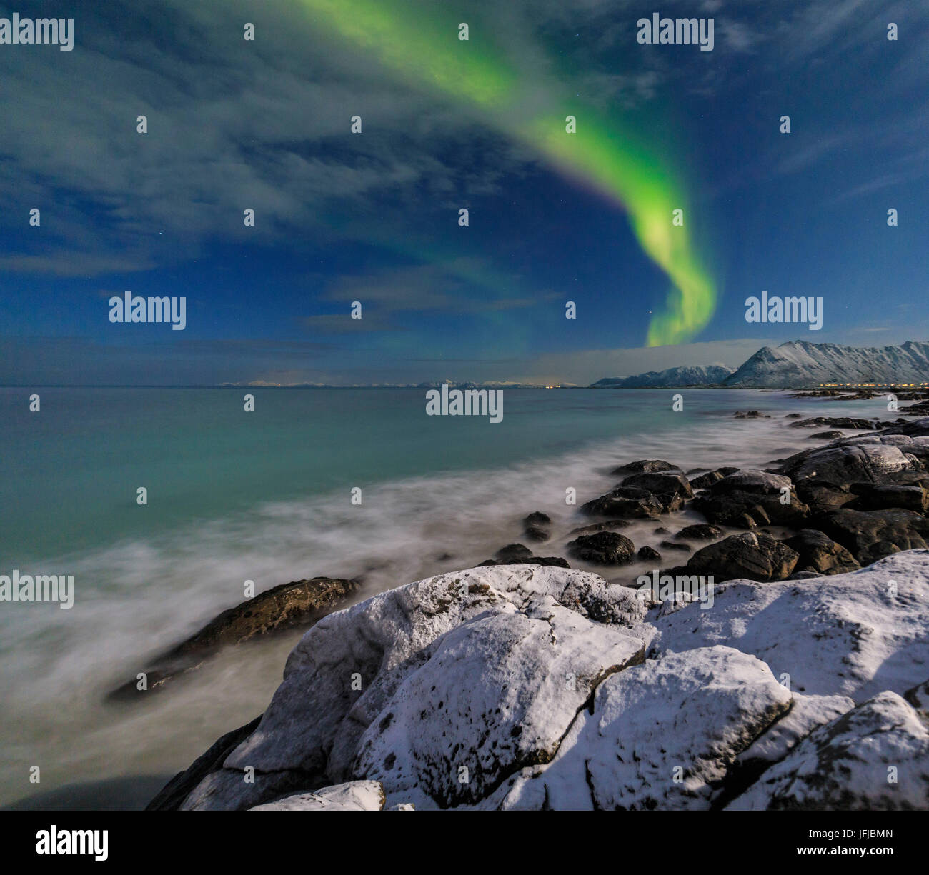 Northern lights on the cold sea of Gymsøyand where the waves break on the rocks, Lofoten Islands Northern Norway Europe Stock Photo