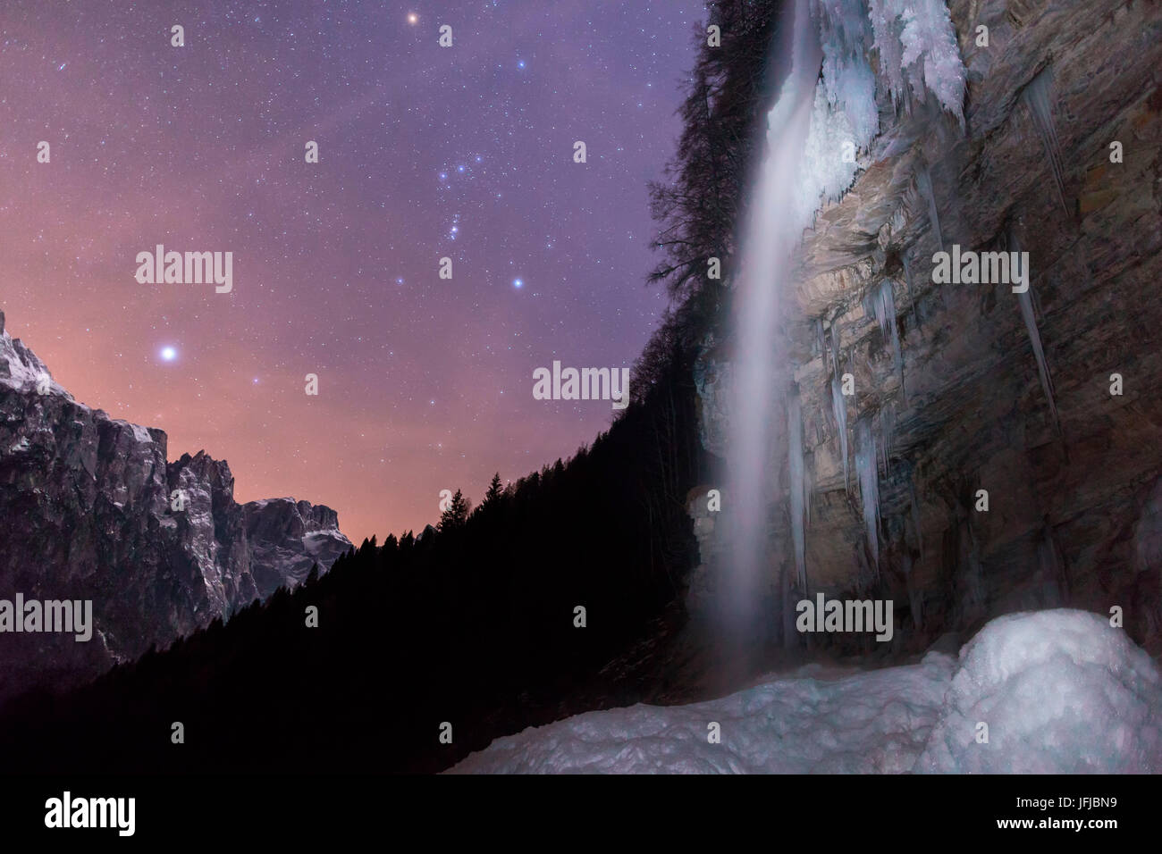The cascade of hell (Cascata dell'Inferno)at the end of the valley of San Lucano, Taibon Agordino, Photographed in the winter under a starry sky with the constellation of Orion, Dolomites, Belluno, Stock Photo