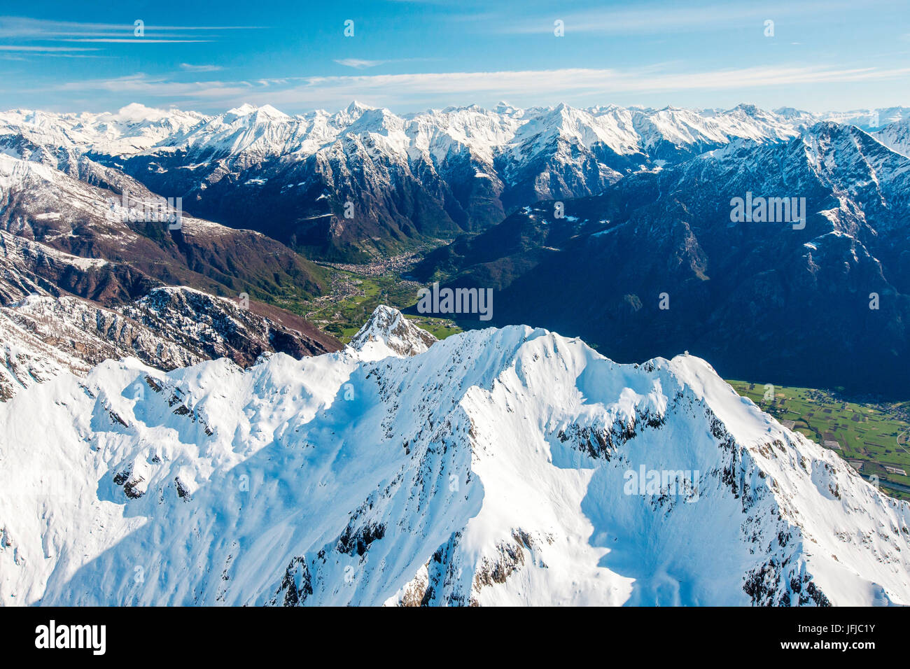 Aerial shot of Sasso Canale covered with snow with Chiavenna behind it, Valchiavenna, Italy, Stock Photo