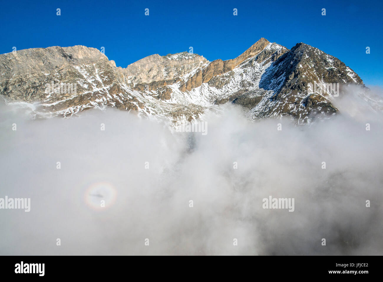 The humidity of clouds and the shadow of helicopter create Brocken spectre in Switzerland, Zermatt, Europe Stock Photo