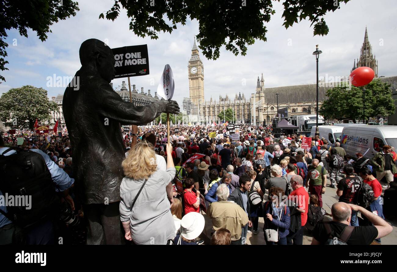 People stand next to the statue of Nelson Mandela in Parliament Square, London, after they march through the city as they took part in an anti-austerity protest. Stock Photo