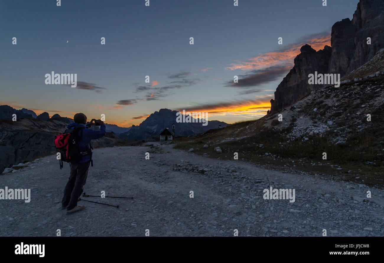 Tre Cime di Lavaredo, Three peaks of lavaredo, Drei Zinnen, Dolomites, Veneto, South Tyrol, Italy, Hiker photographs sunset at Tre Cime di Lavaredo Stock Photo