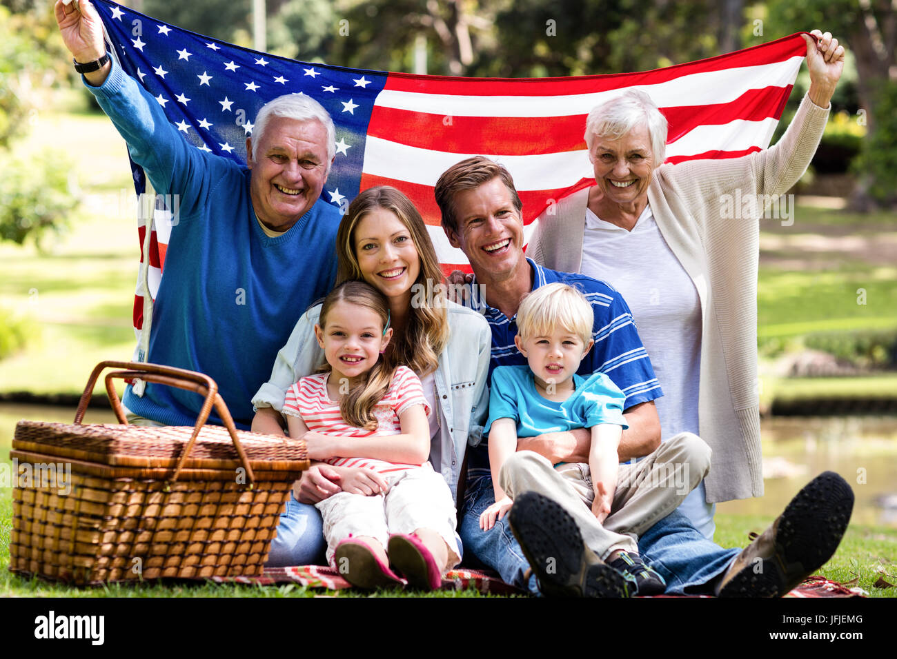 Multi-generation family holding american flag in the park Stock Photo