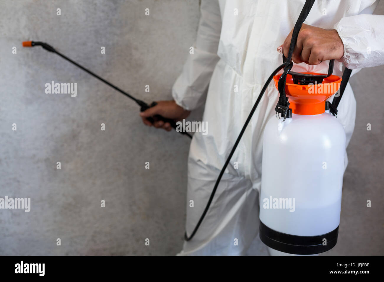 Midsection of manual worker using spray on wall Stock Photo