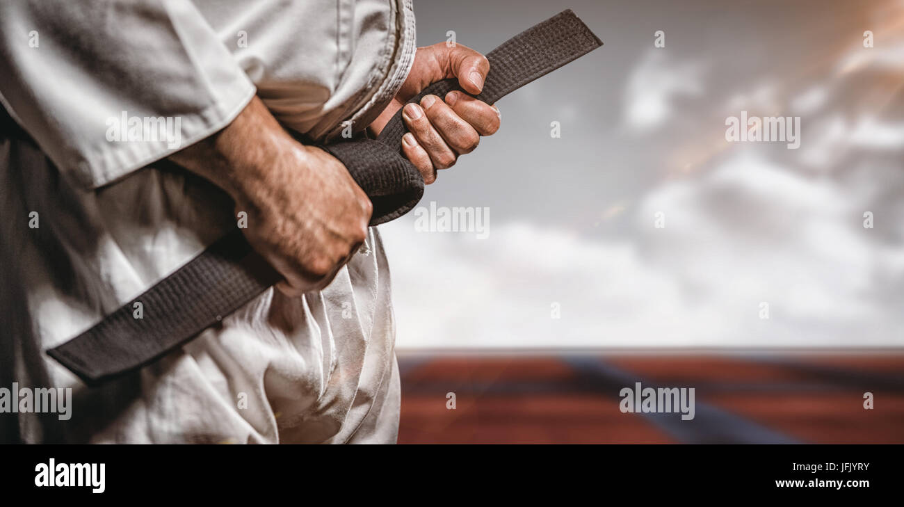 Composite image of fighter tightening karate belt Stock Photo Alamy