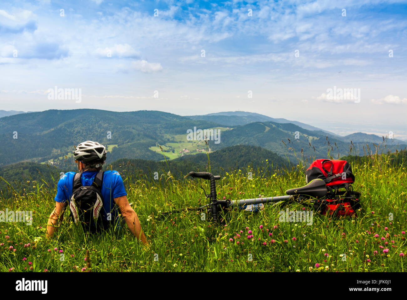Rear view of man relaxing on grass and looking at mountains Stock Photo