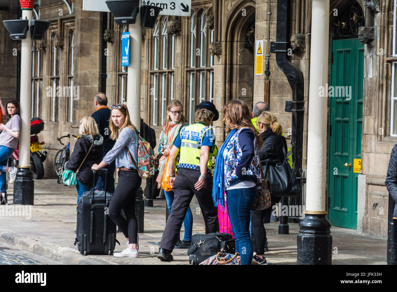 A candid street scene outside Shrewsbury train station. A community support officer is heading inside the building while commuters wait for transport. Stock Photo