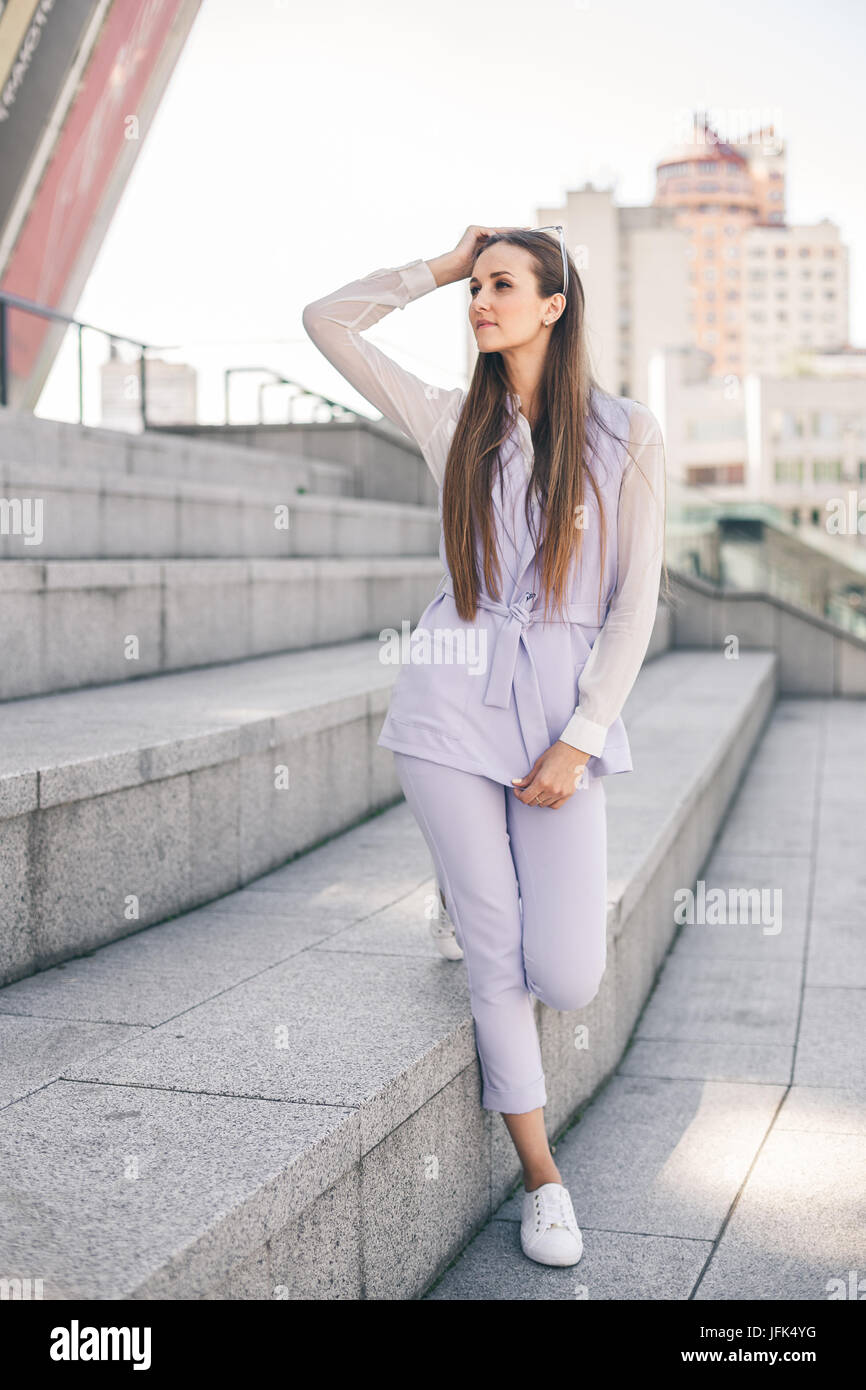 Beautiful young woman in a business purple suit against a city ...