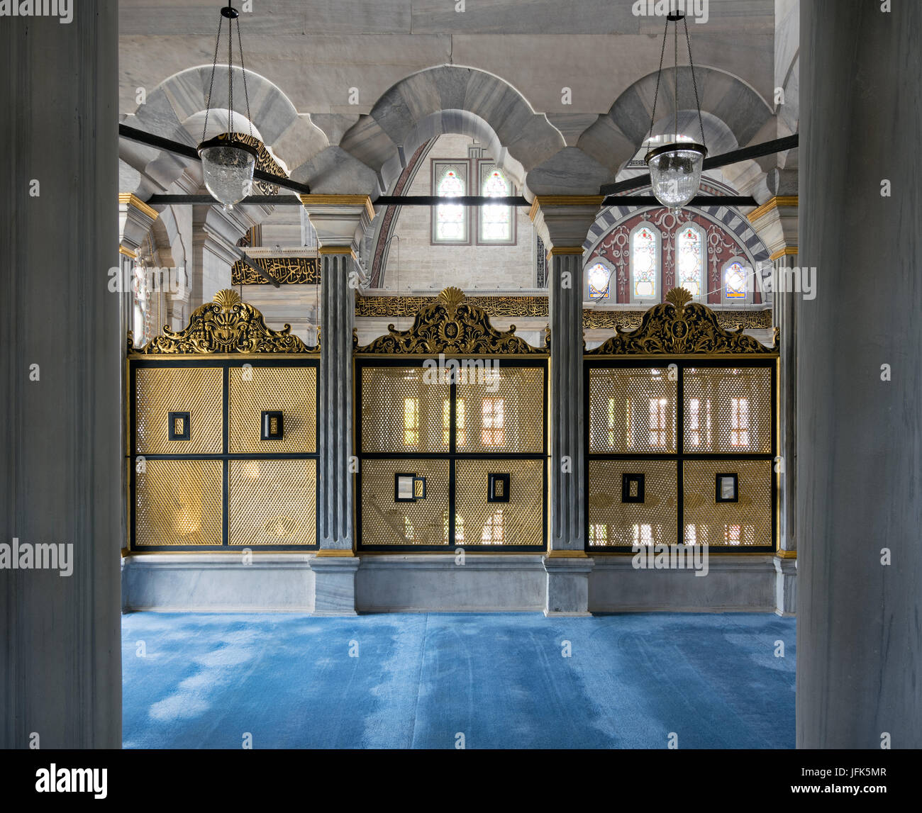 Three gold painted decorated Interleaved wooden windows (Mashrabiya) framed by three marble arches, marble wall and blue carpet on the second floor te Stock Photo