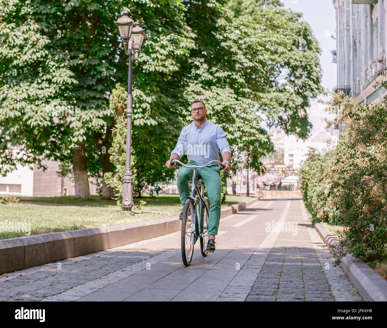 Businessman riding bicycle to work on urban street in morning. Stock Photo