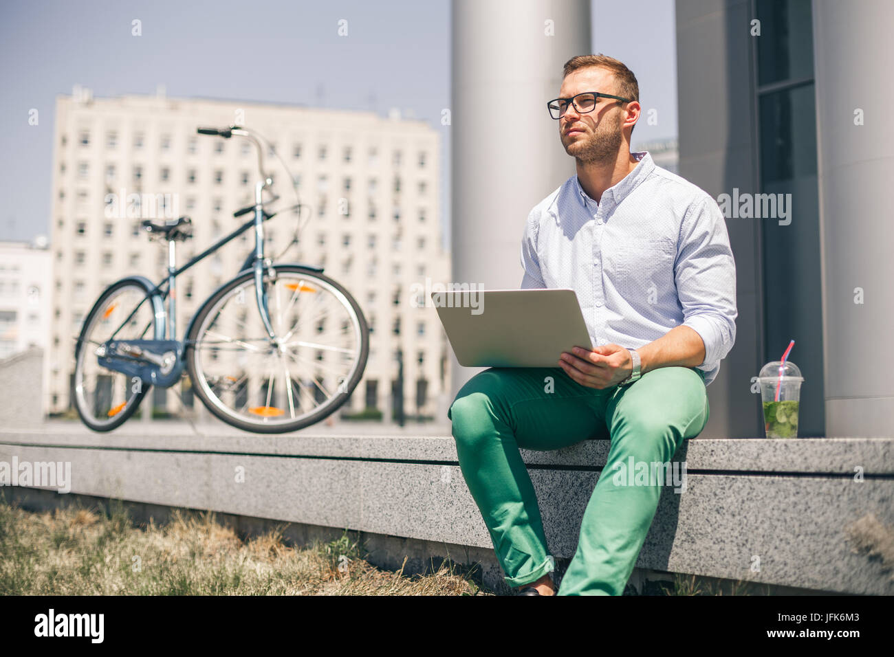 Business man with laptop and sport bike sitting in city. Stock Photo