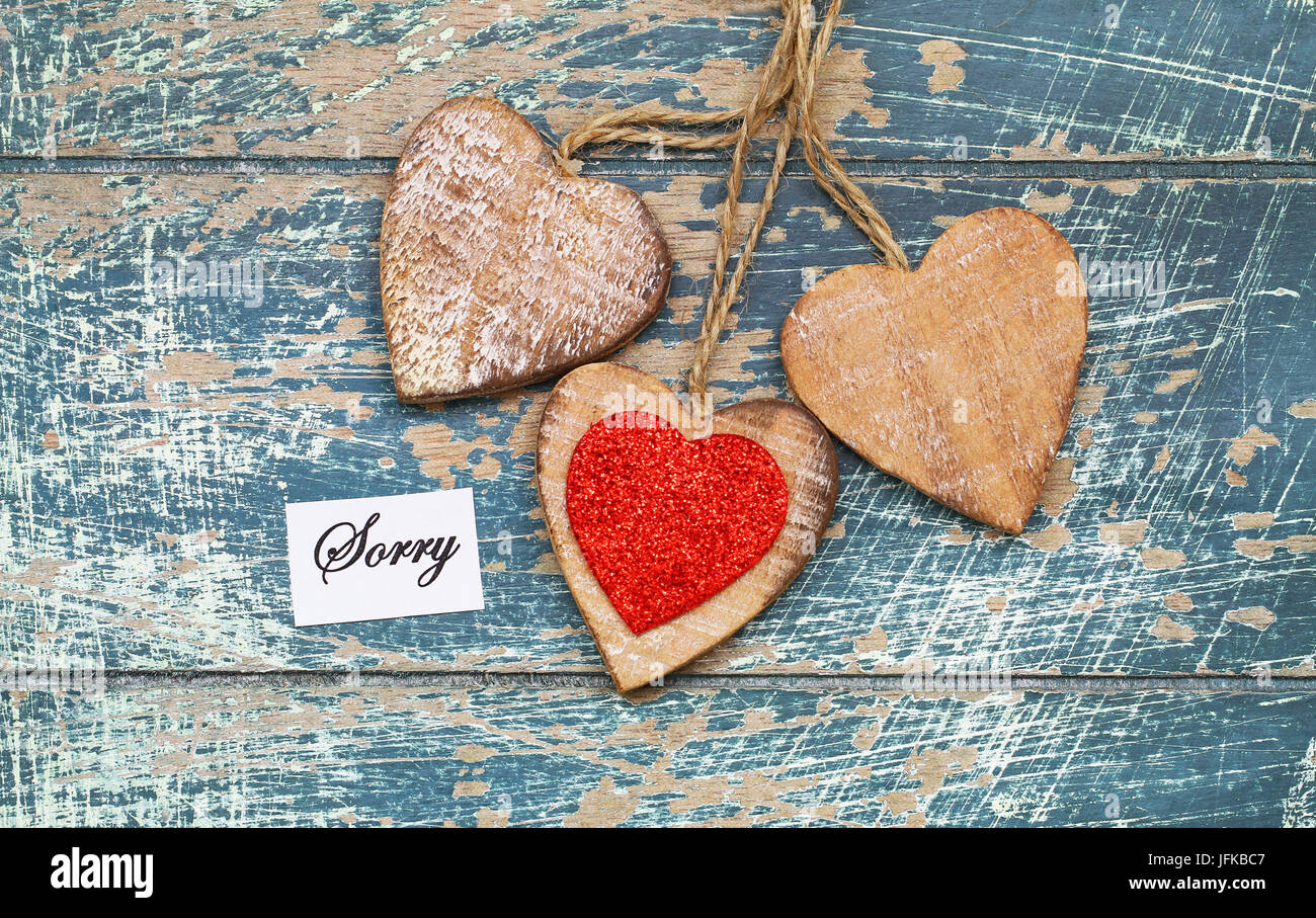 Sorry card with three wooden hearts on rustic surface Stock Photo
