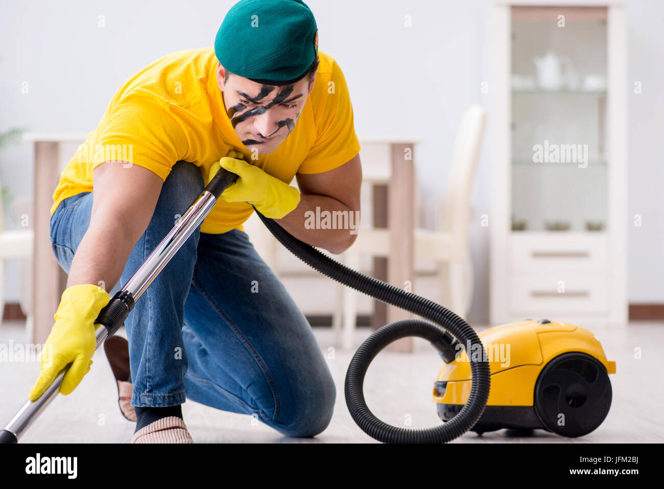 Funny man in military style cleaning the house Stock Photo