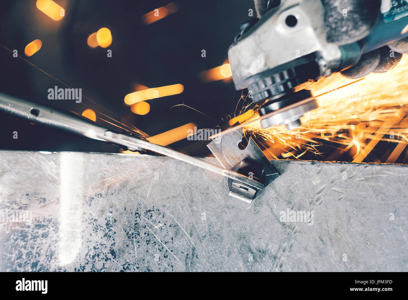 Cutting of curlicue hook using hand angle grinder and spreading sparks all around Stock Photo