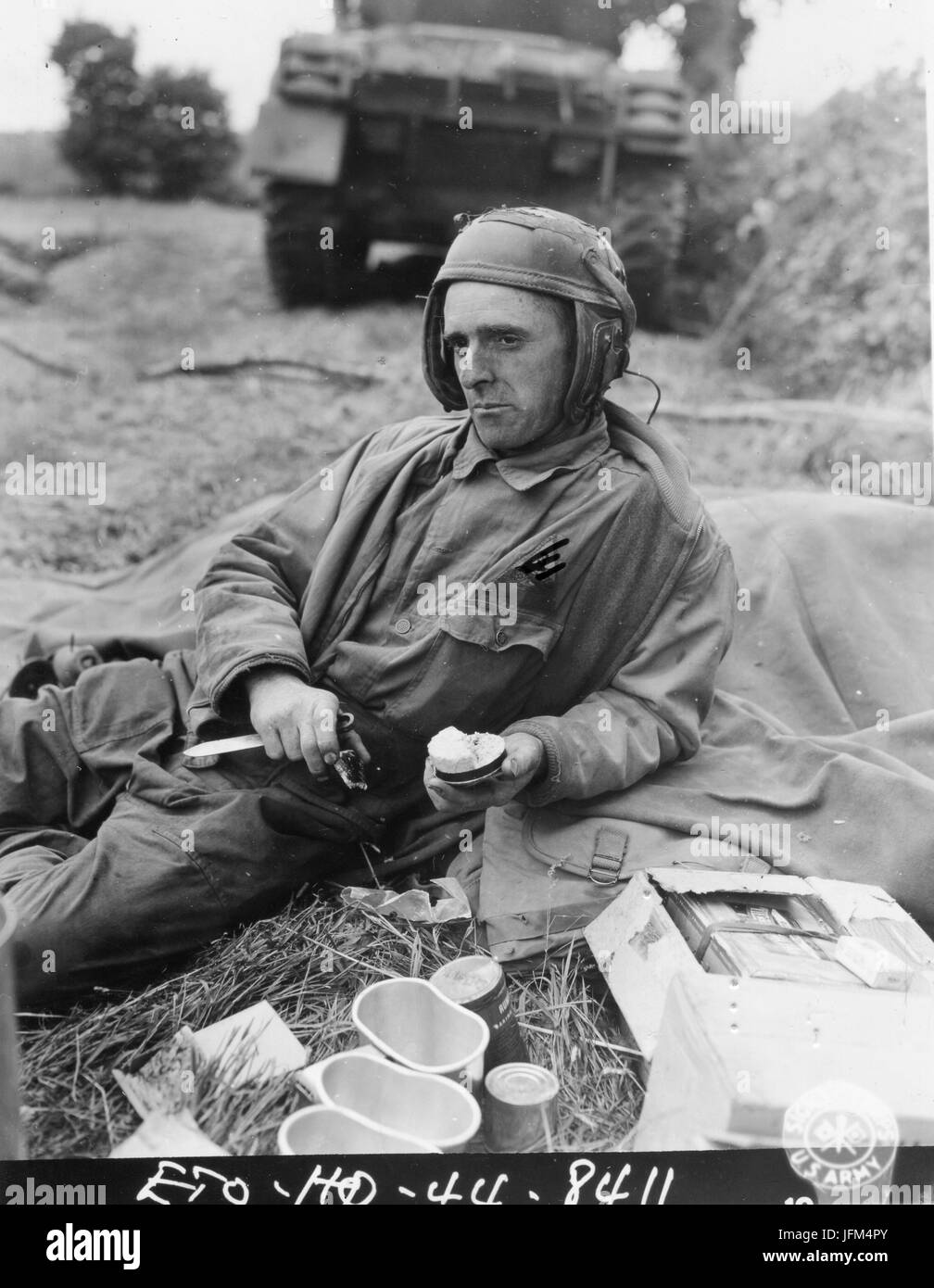 PFC Jerry C. Coleman, assistant driver of a tank attached to an armored unit in France, takes time out during a lull in the action to eat his K rations. July, 1944. Stock Photo