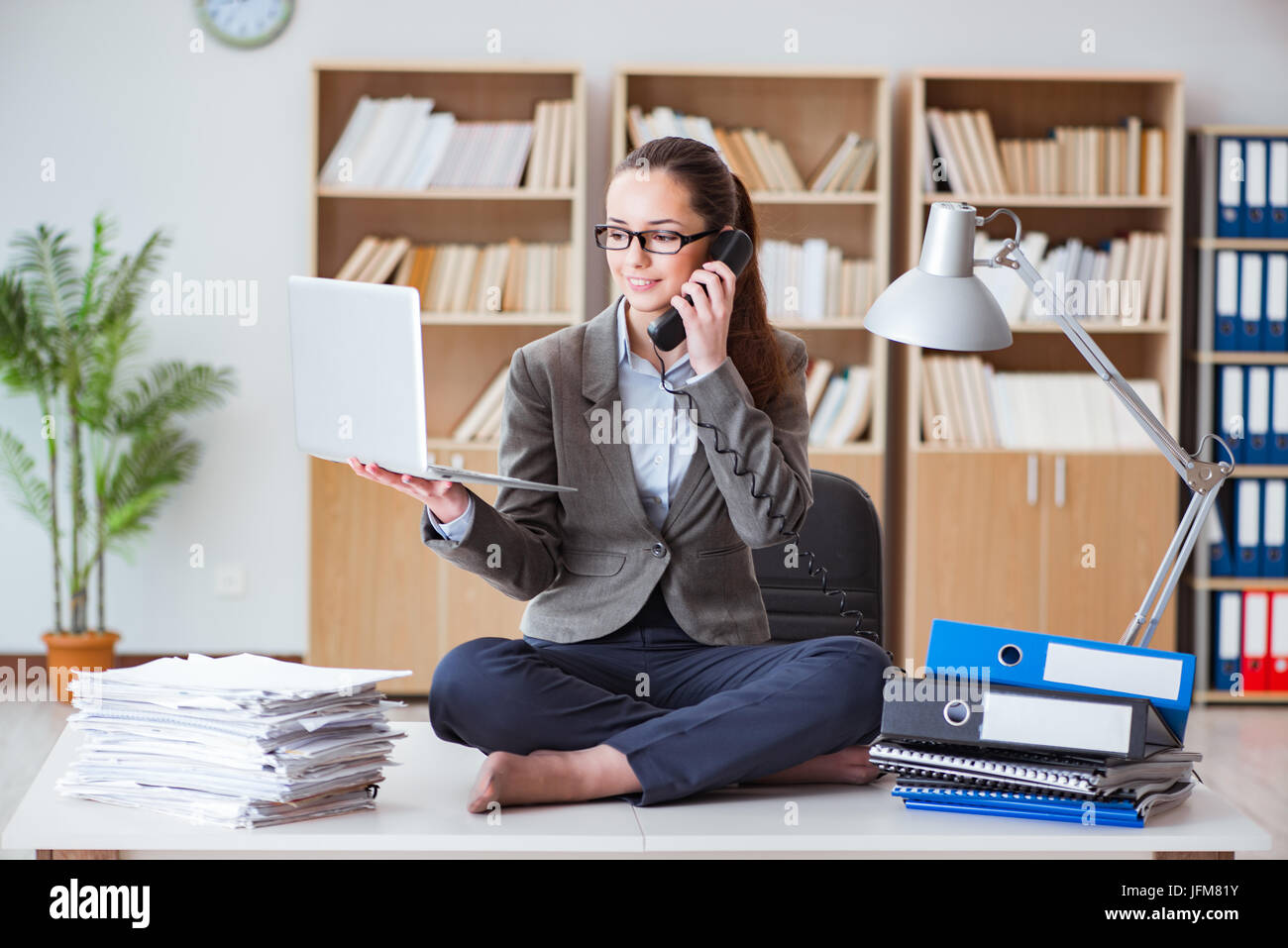 Busy angry businesswoman sitting on the desk in office Stock Photo - Alamy
