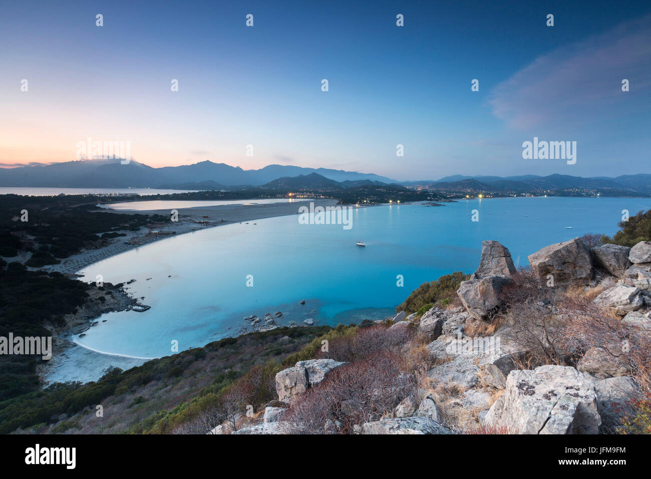 Top view of the bay with sandy beaches and lights of a village at dusk Porto Giunco Villasimius Cagliari Sardinia Italy Europe Stock Photo
