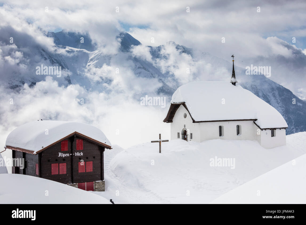 Clouds above the mountain huts and church covered with snow Bettmeralp district of Raron canton of Valais Switzerland Europe Stock Photo