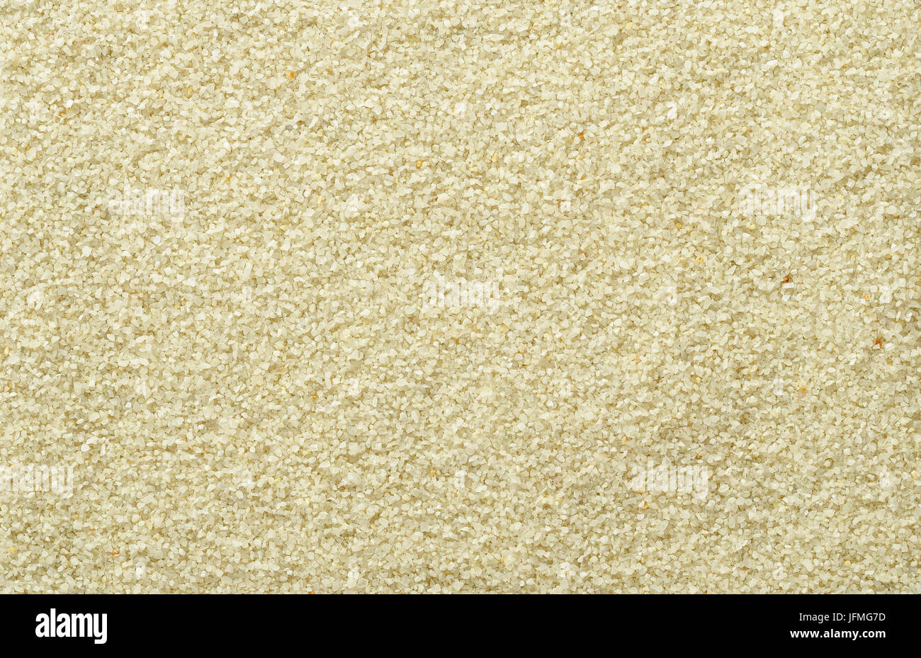 Smooth and even sand surface. Light brown and ocher colored grains of sand. Backgrounds. Closeup macro photo directly from above. Stock Photo