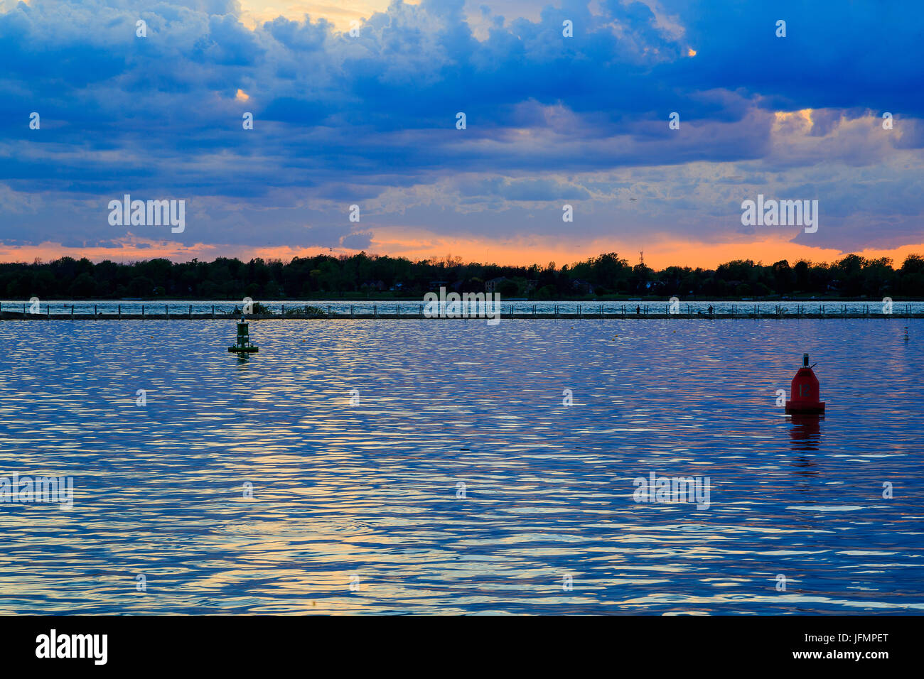 Boats, rocky shore, sunset on Lake Erie looking from Buffalo Park system. Sky is blue with orange ting. Stock Photo