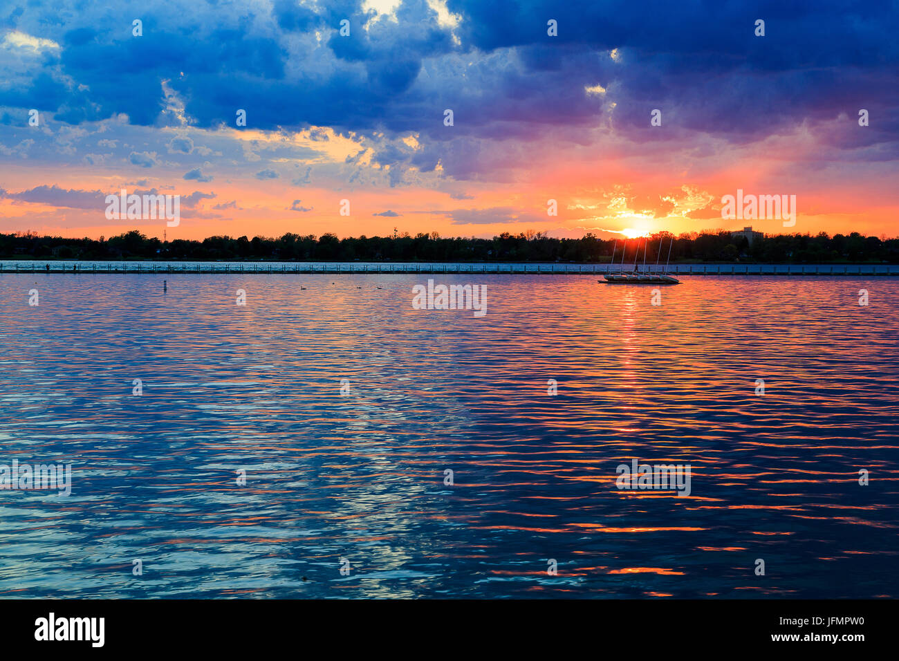 Boats, rocky shore, sunset on Lake Erie looking from Buffalo Park system. Sky is blue with orange ting. Stock Photo