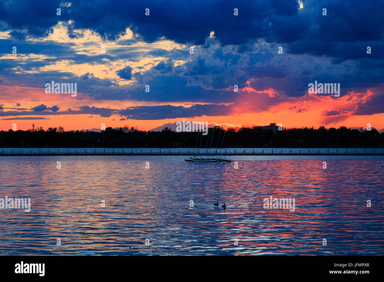 Boats, rocky shore, sunset on Lake Erie looking from Buffalo Park system. Sky is blue with orange ting. Stock Photo