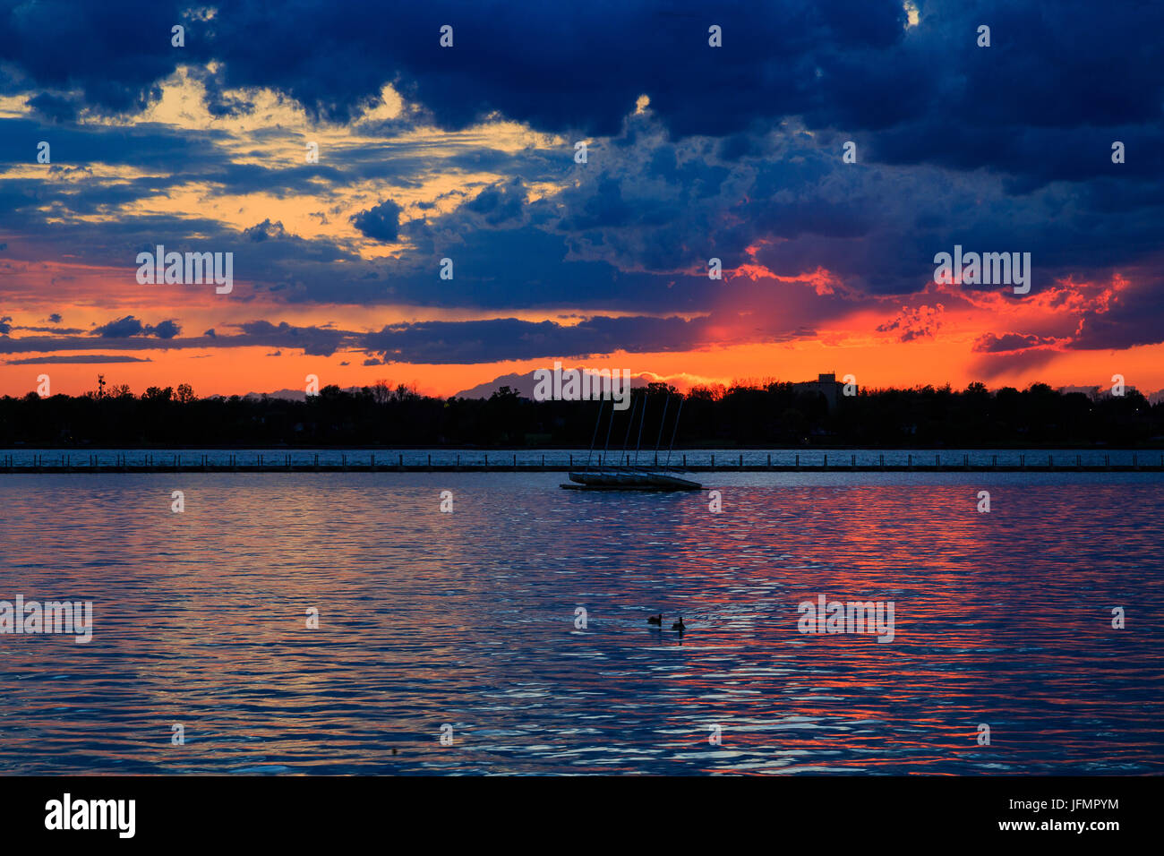 Boats, rocky shore, sunset on Lake Erie looking from Buffalo Park system. Sky is blue with orange ting. Stock Photo