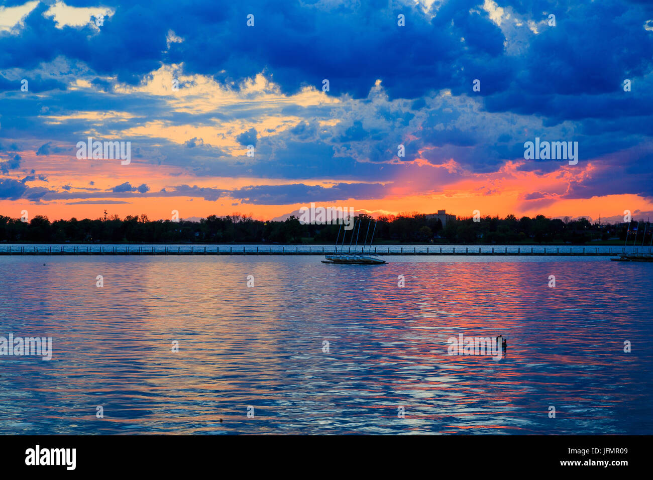 Boats, rocky shore, sunset on Lake Erie looking from Buffalo Park system. Sky is blue with orange ting. Stock Photo