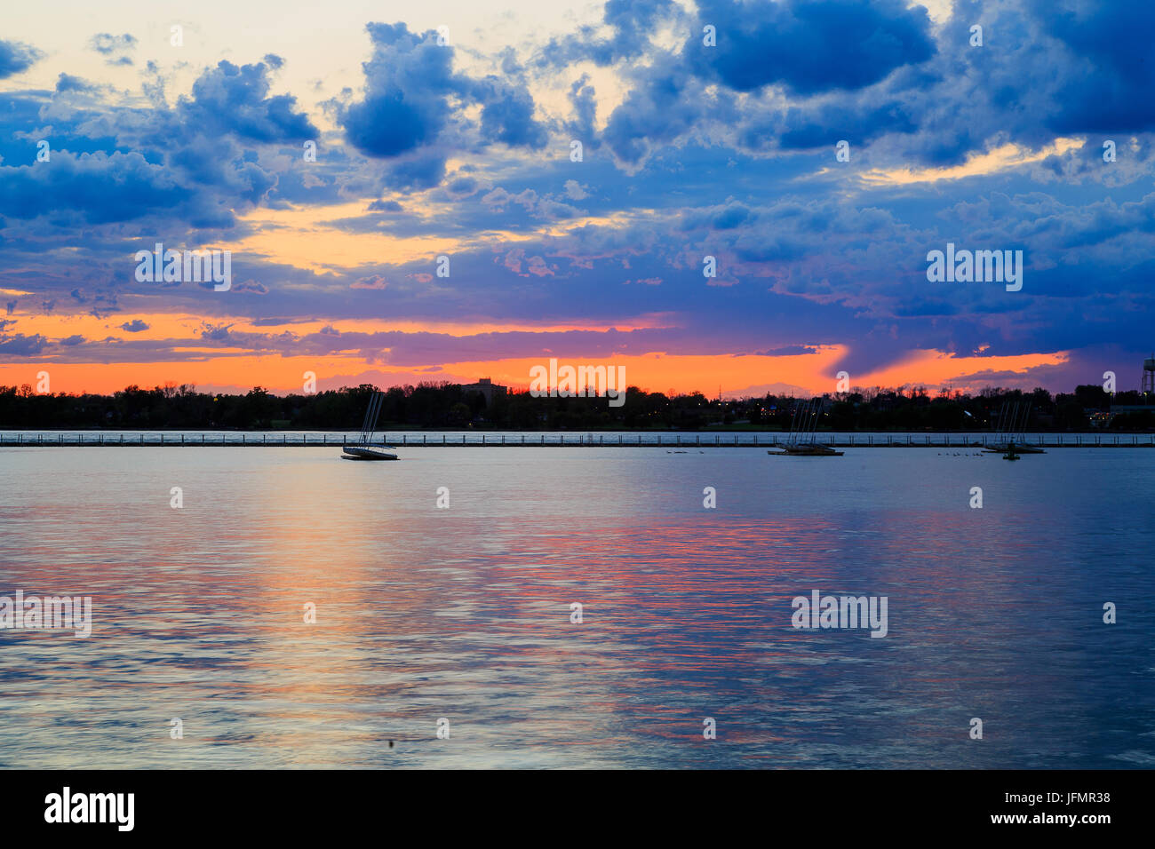 Boats, rocky shore, sunset on Lake Erie looking from Buffalo Park system. Sky is blue with orange ting. Stock Photo