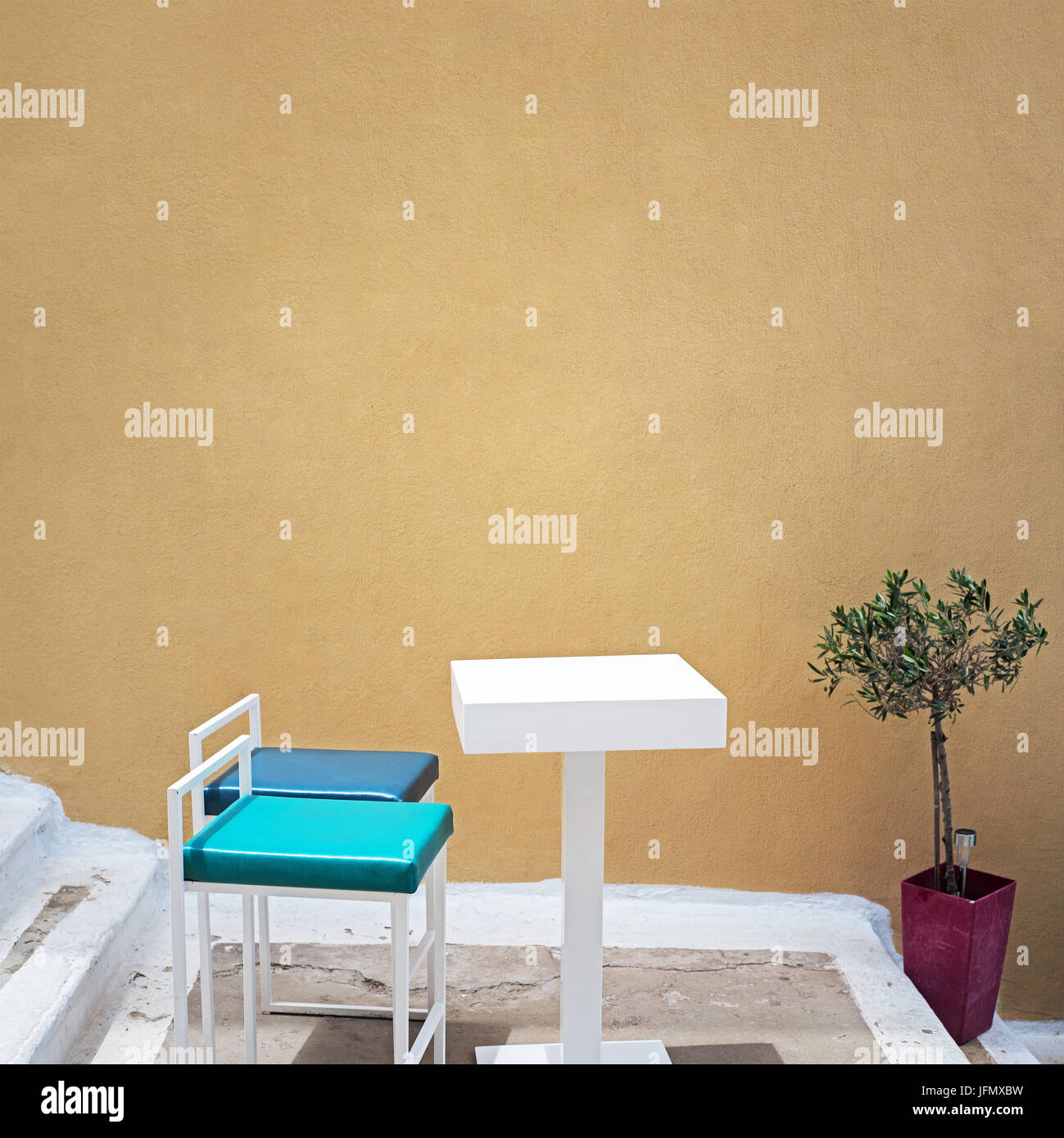 outdoor table and two chairs near the grunge wall Stock Photo