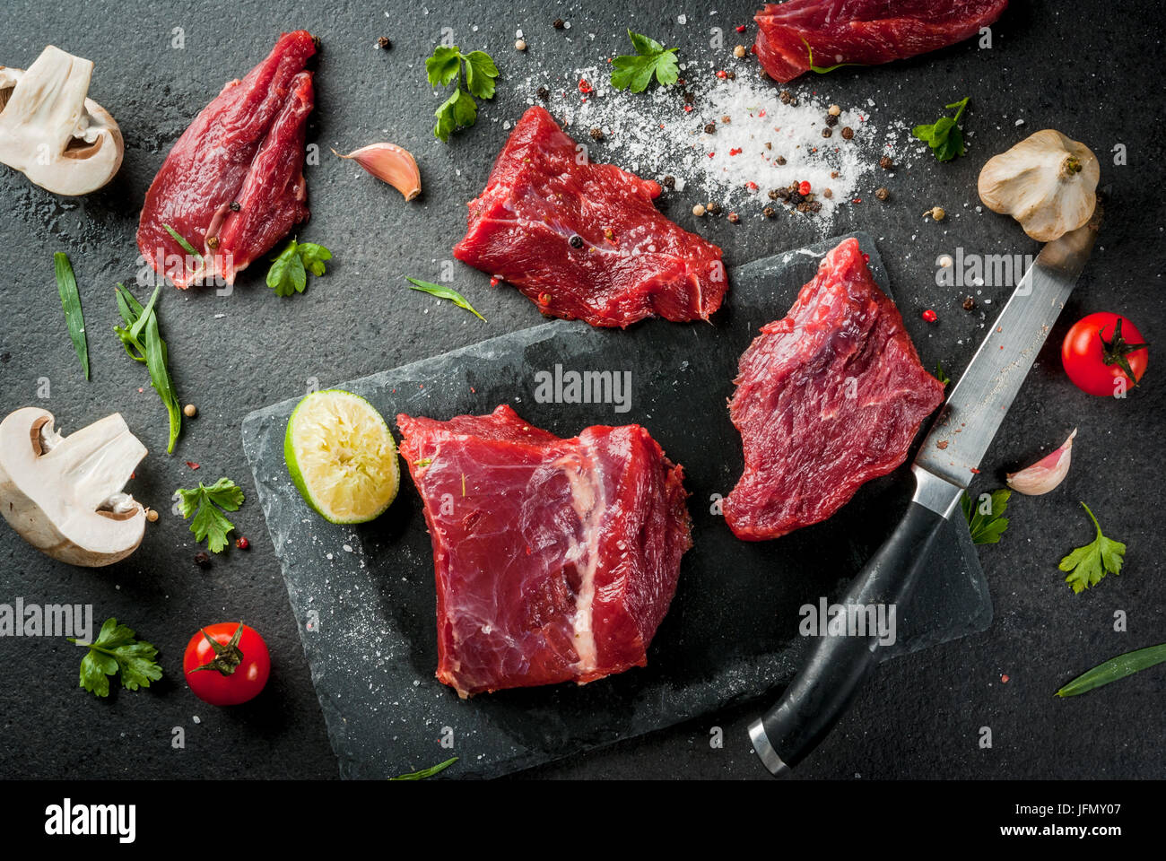 Fresh raw beef meat tenderloin steaks on a slate cutting board on black ...