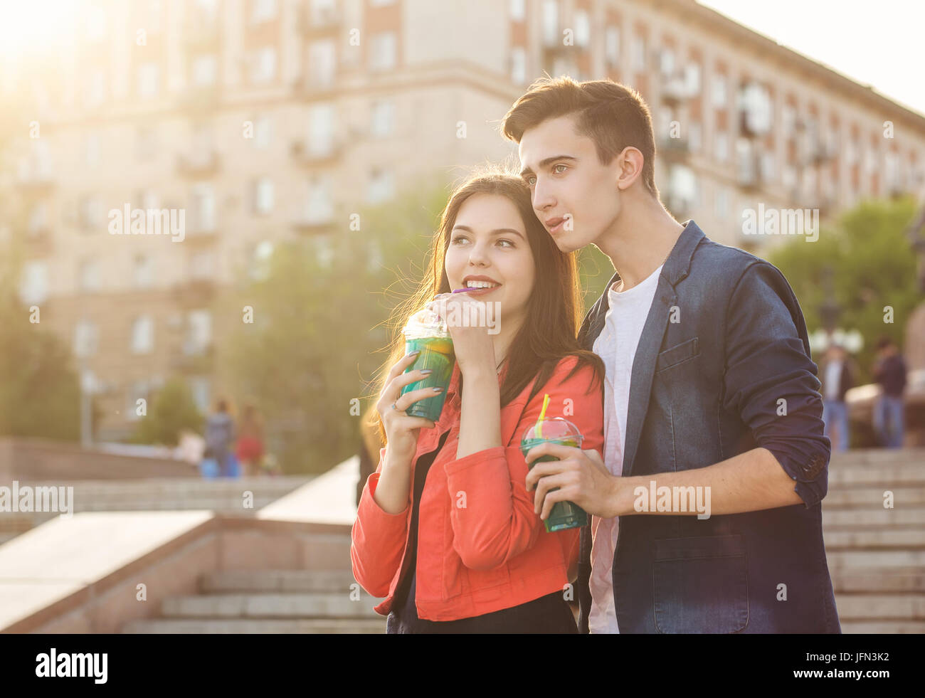 Teenagers drink fruit fresh from glasses. They are talking. A couple in love on a date. Romance of first love. Stock Photo