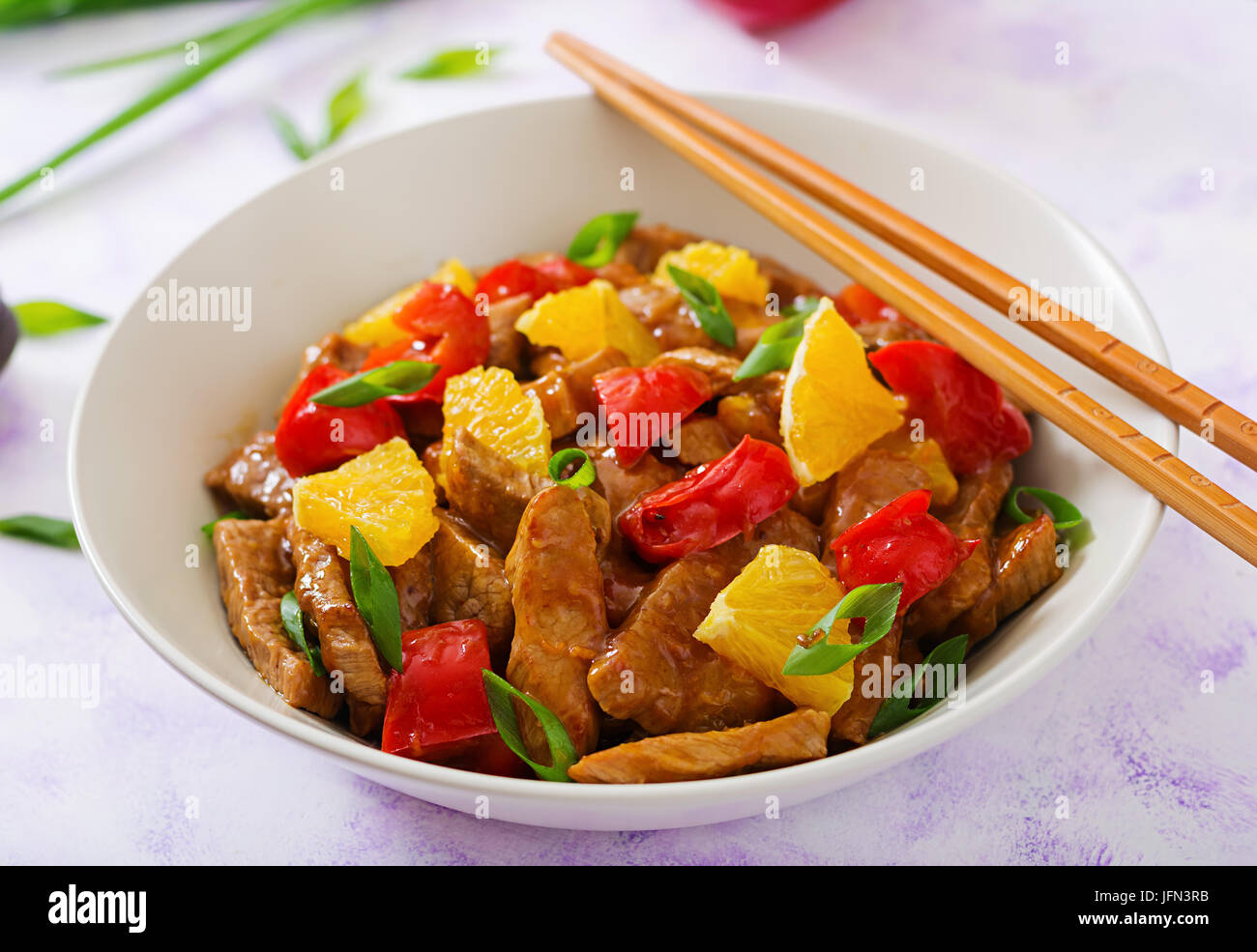 Veal fillet - stir fry with oranges and paprika in sweet and sour sauce on a light background Stock Photo