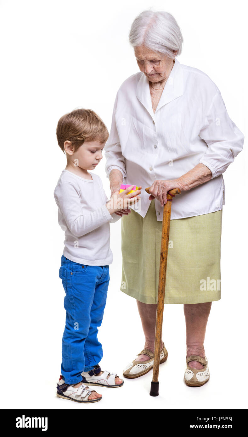 Young boy and his great grandmother trying to solve cube puzzle over white background Stock Photo