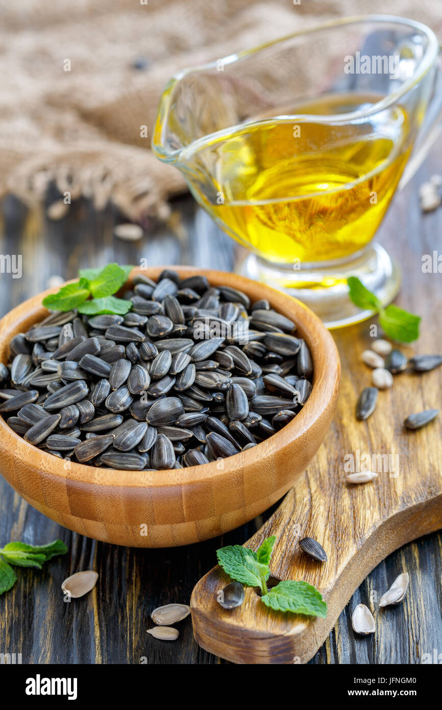 Wooden bowl with sunflower seeds and oil in glass cup. Stock Photo