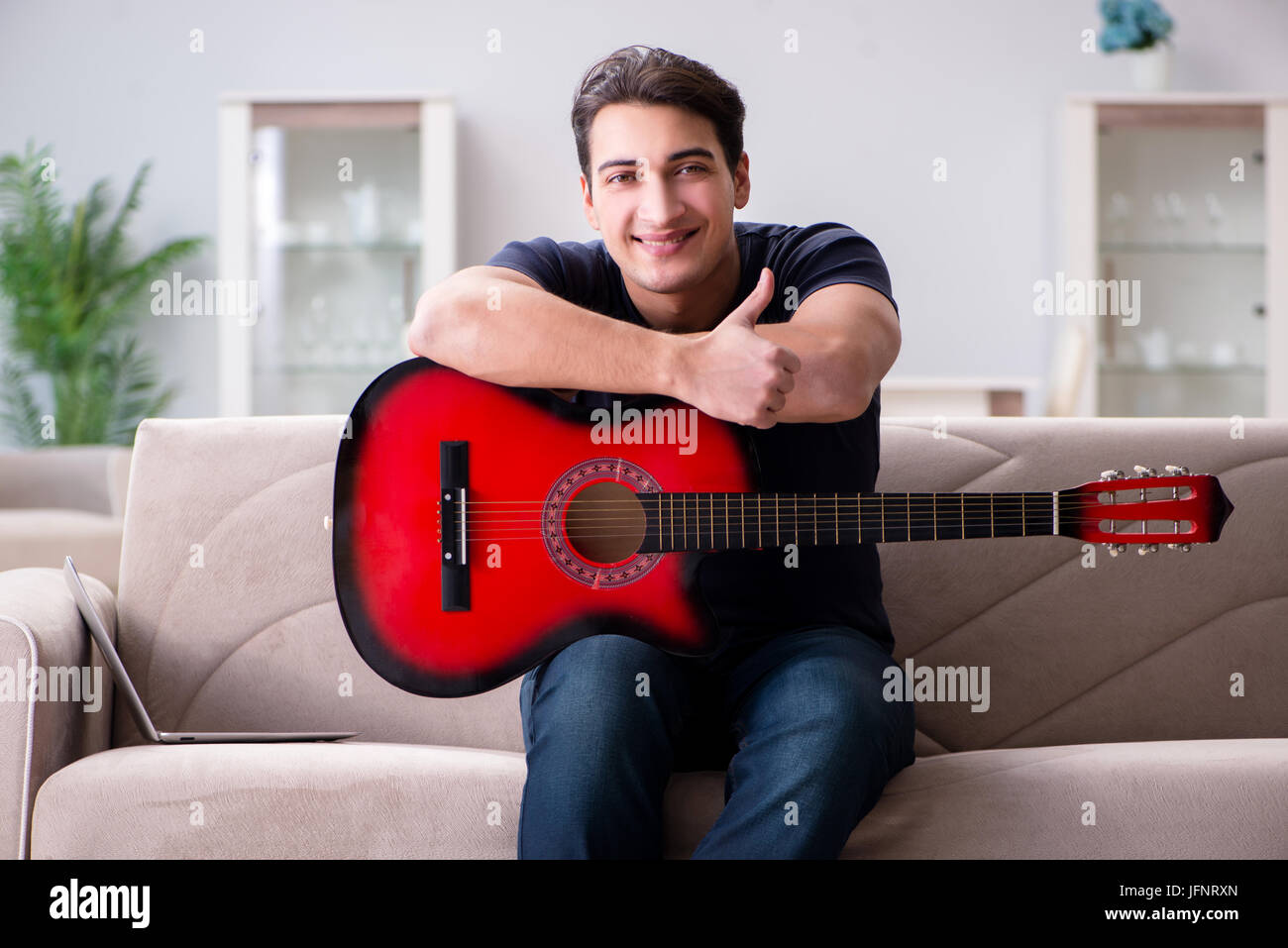 Young man practicing playing guitar at home Stock Photo - Alamy