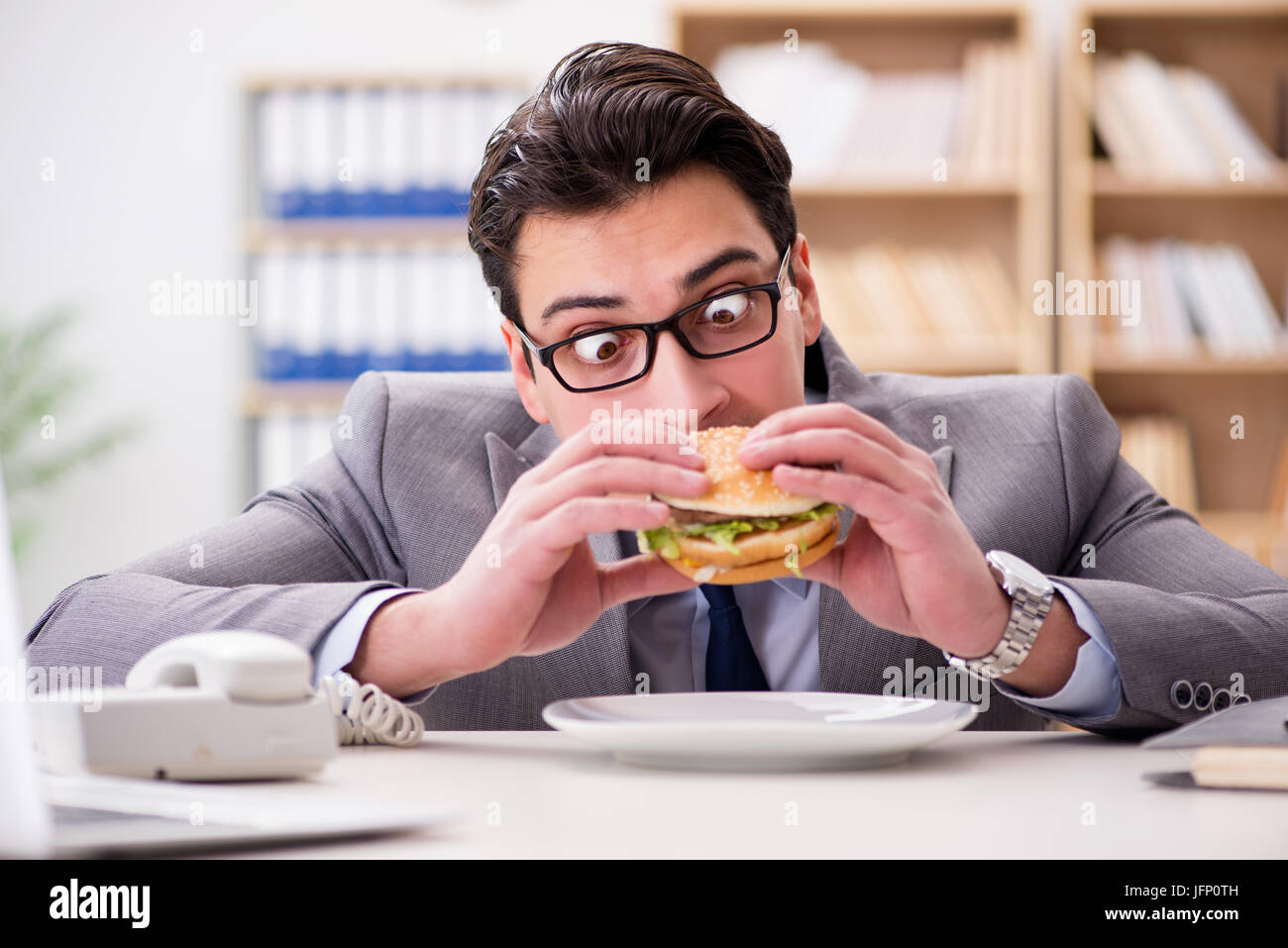 Hungry funny businessman eating junk food sandwich Stock Photo Alamy
