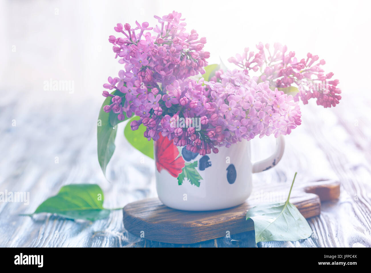 Bouquet of lilacs in an old enamel mug, toning. Stock Photo