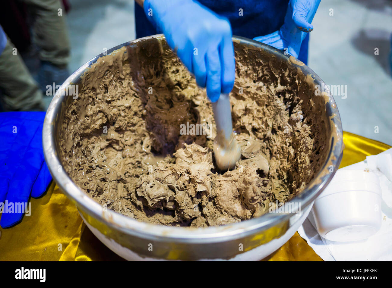 Home made chocolate ice cream in a metal bowl. Human hand with blue