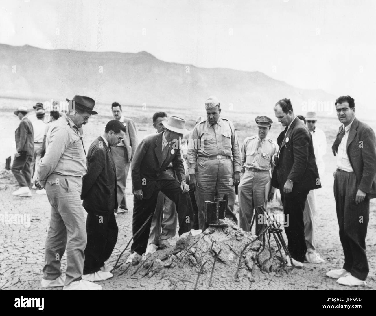 Ground Zero showing the melted remains of the atomic bomb tower after the first atomic test viewed by Dr. J. R. Oppenheimer, Director of Los Alamos Atomic Bomb Project and Physicist, (center with light hat)  and Maj General Leslie R. Groves (center), Chief of Manhattan Engineering District, . July, 1945. Alamogordo, NM, July 16, 1945 Stock Photo
