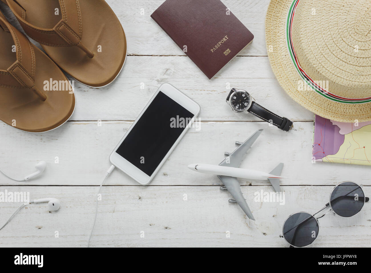 Top view essential accessories to travel concept.items for trip slipper,notebook,map,passport airplane,mobile phone,sunglasses on rustic wooden table  Stock Photo