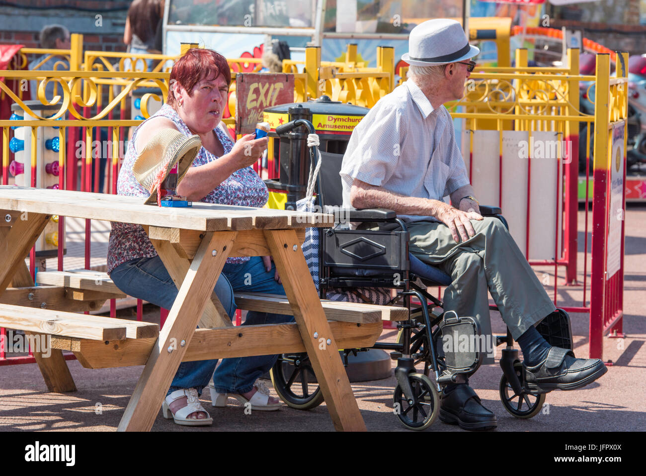 Man in a wheelchair with a woman in the amusement park in Dymchurch ...