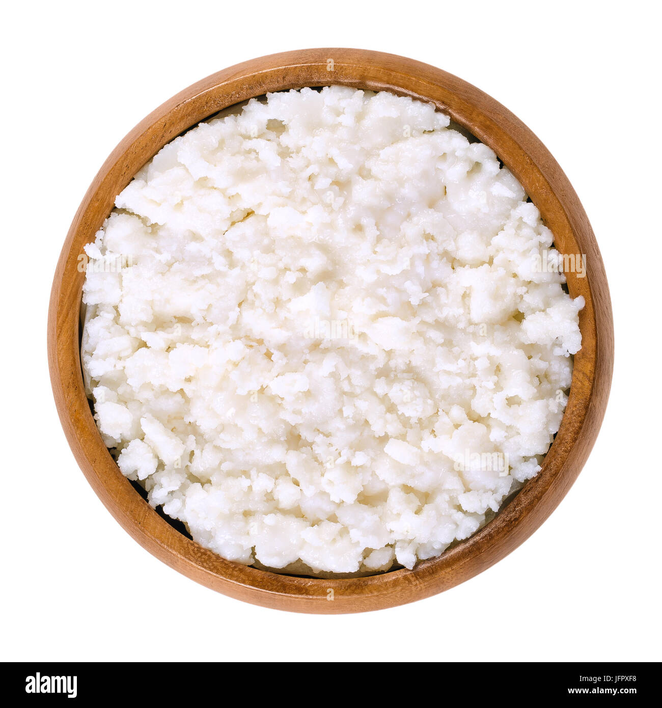 Coconut puree in wooden bowl. Grated flesh and meat of coconut kernels. White, edible and raw food paste and cream. Isolated macro food photo close up Stock Photo