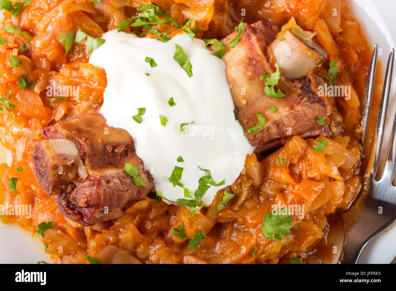Cabbage stew with Smoked Pork Ribs, cream and green parsley Served in white plate Stock Photo