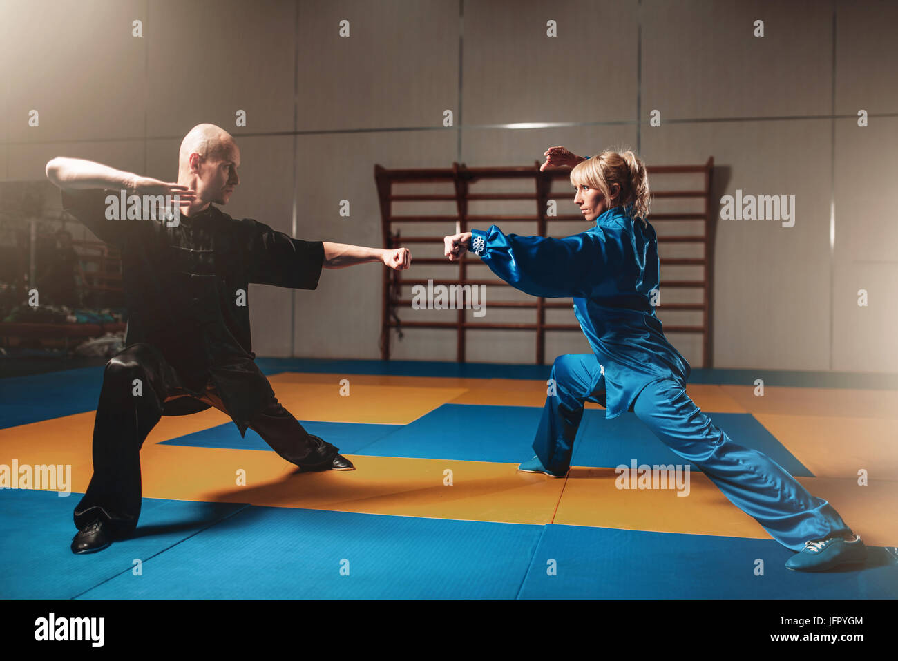 Male and female wushu fighters exercises indoor, martial arts. Sparring