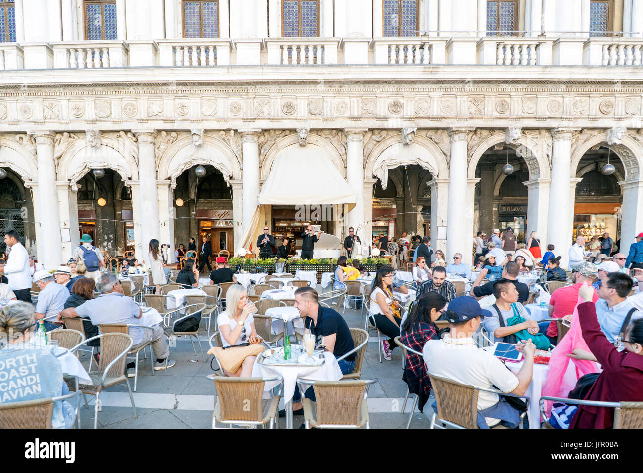 Venice, Veneto / Italy. May 21, 2017: Terraces with drinking people and musicians playing at the Great Cafe Chioggia in St. Mark's Square Stock Photo