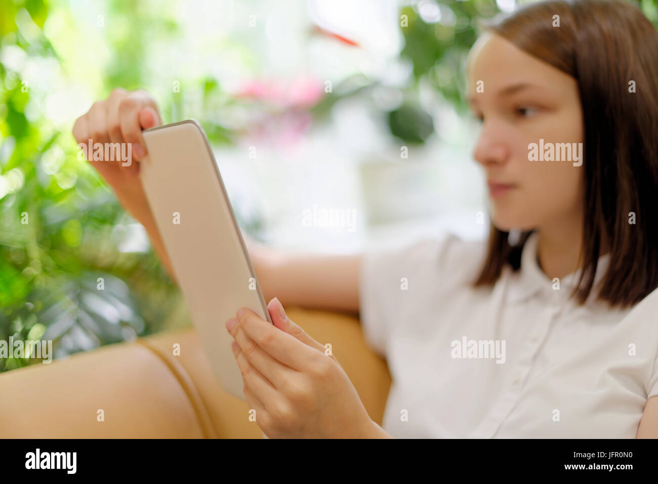 People: young girl, student, making use of tablet computer or e-book reader, in a library or bookstore, selective focus on hands Stock Photo