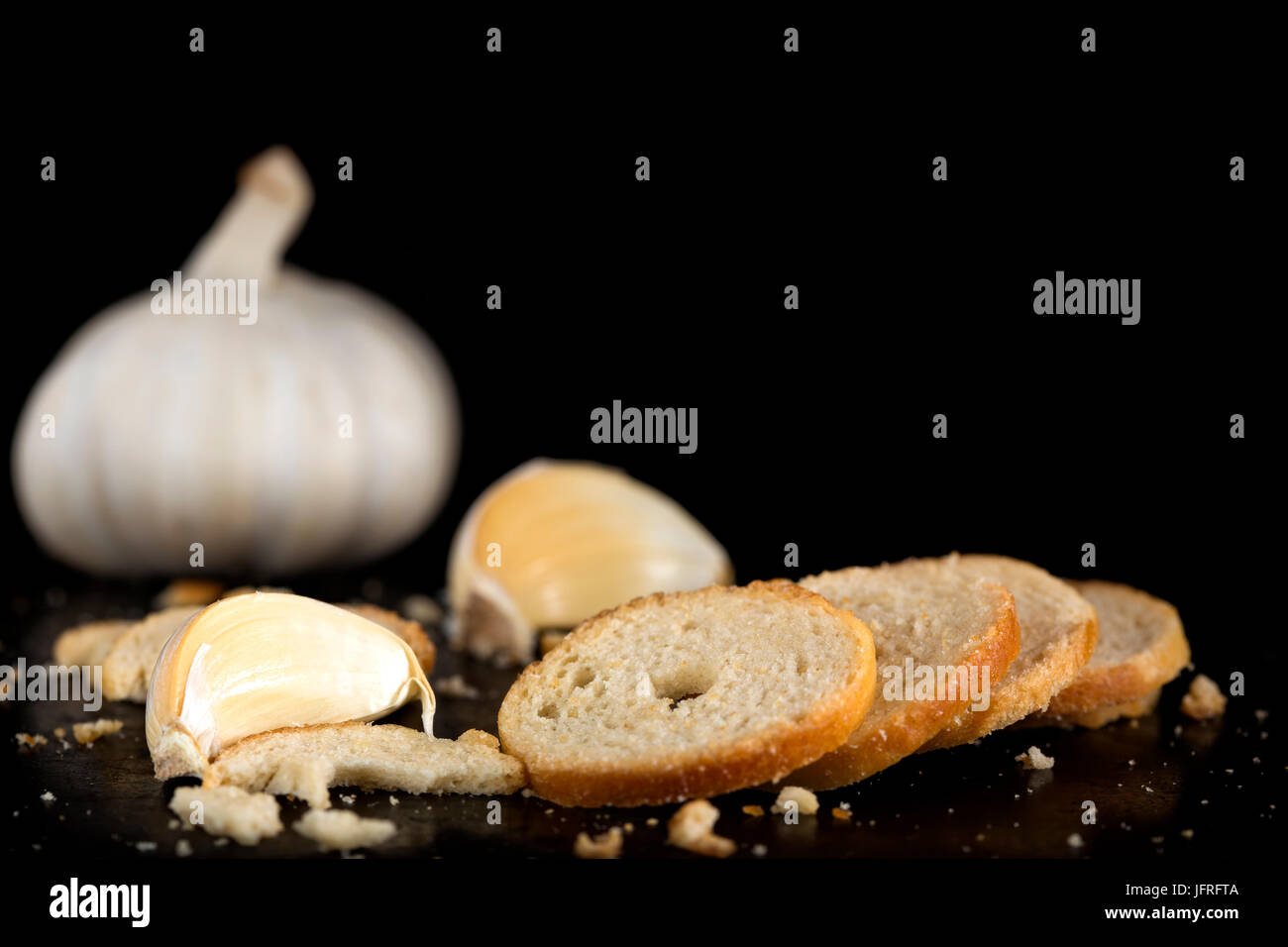Mini rolls of baked bread and garlic on dark background Stock Photo